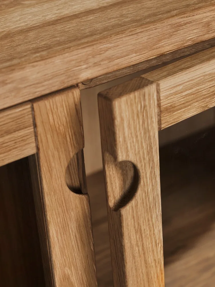 Due pannelli in legno chiaro, ciascuno con un intaglio a forma di cuore, su un mobile.