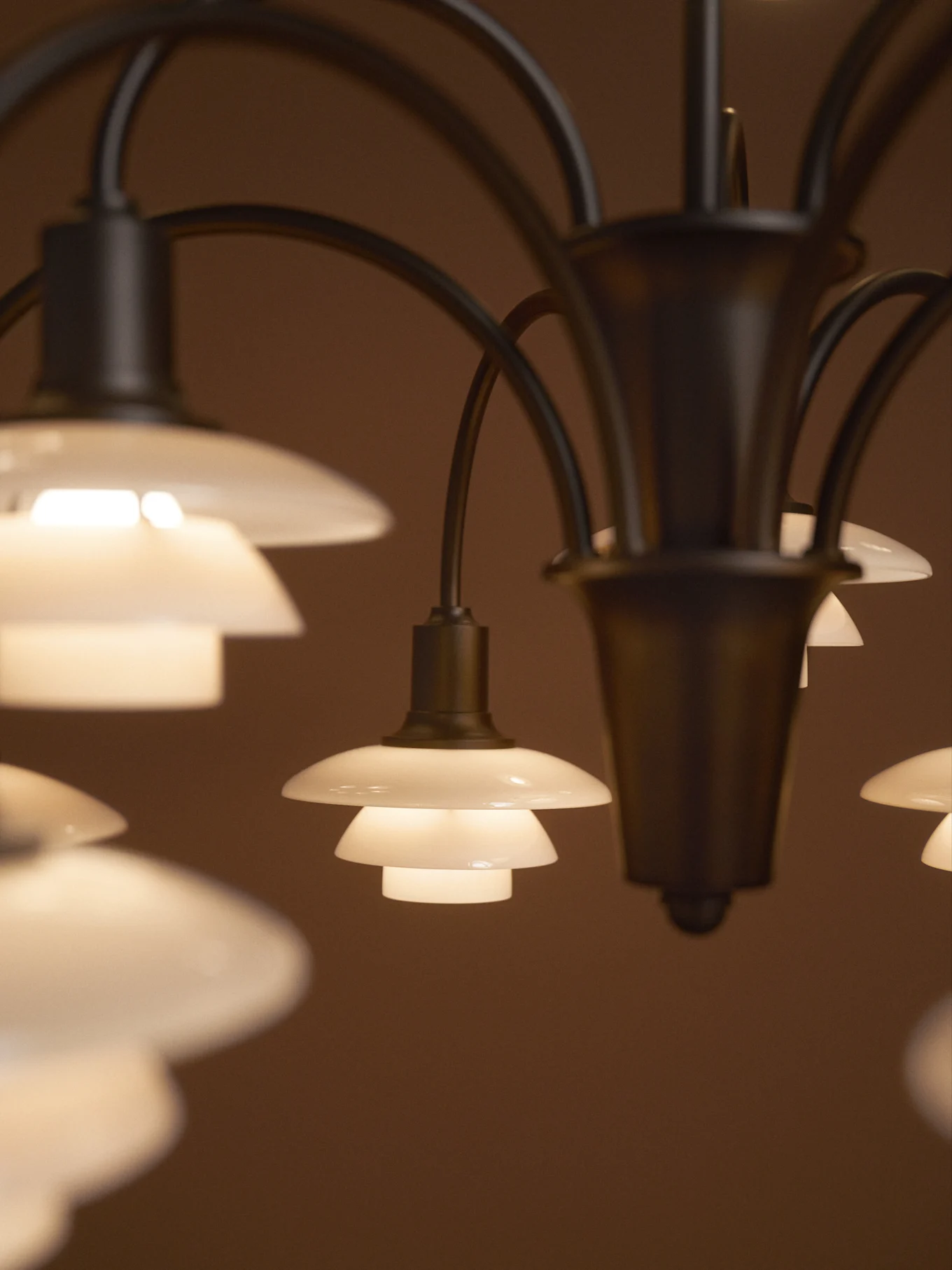 Lampadario con diverse tonalità di vetro smerigliato a più livelli, luminose, su sfondo scuro.