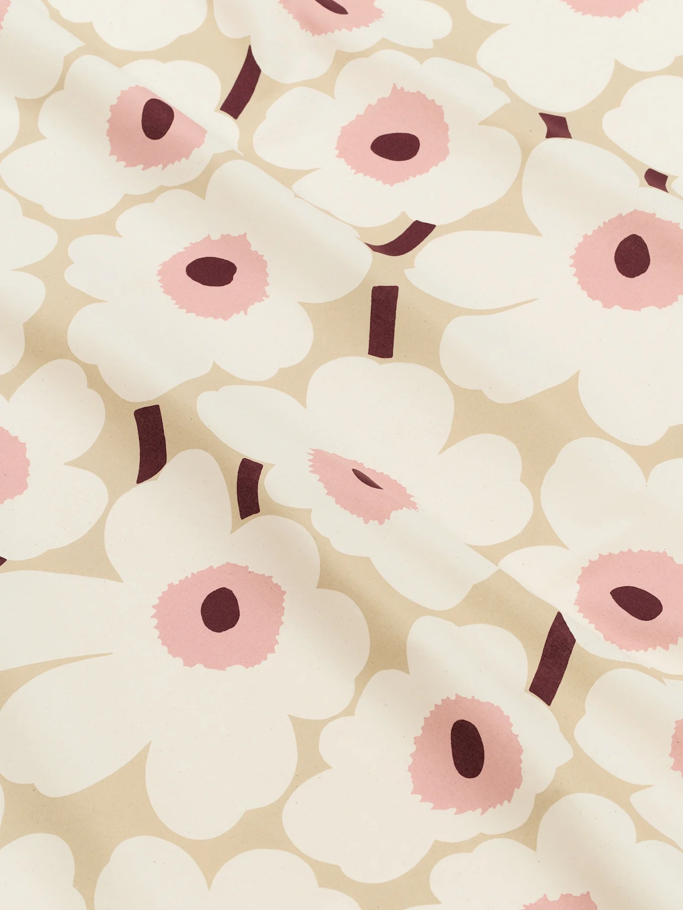 Primo piano di un tessuto beige chiaro con un motivo di grandi fiori bianchi stilizzati con centri rosa e steli bordeaux scuro.