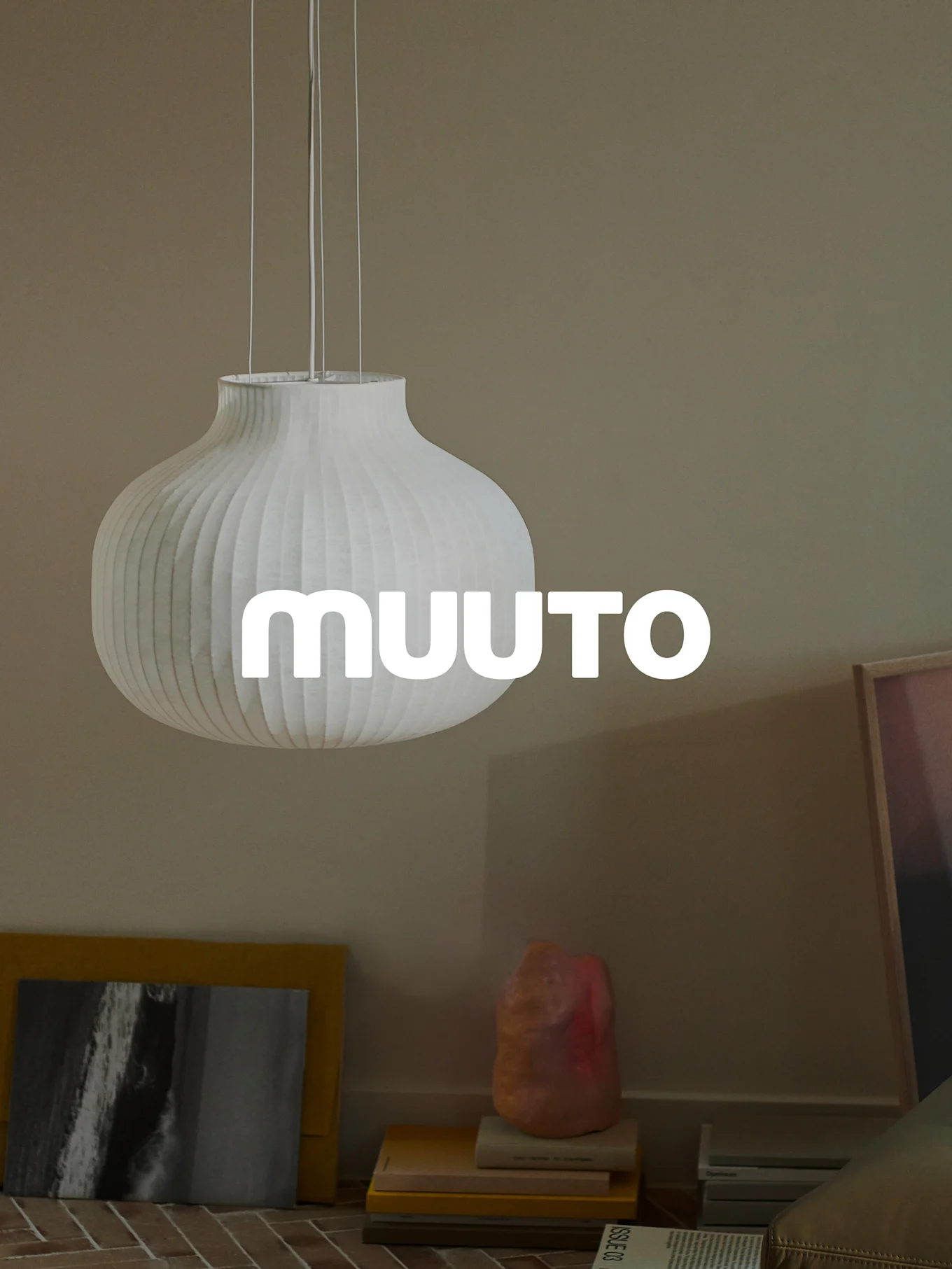 Lampada a sospensione bianca a coste a forma di zucca con logo 'MUUUTO', in una stanza beige.