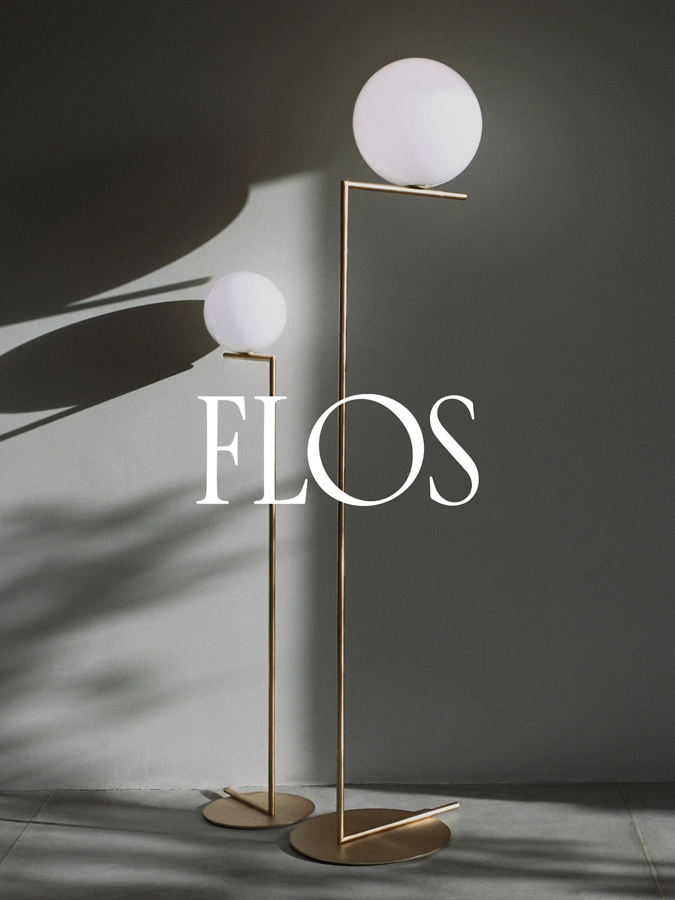 Due lampade da terra moderne con diffusori sferici bianchi e cornici in metallo dorato, con il logo Flos.