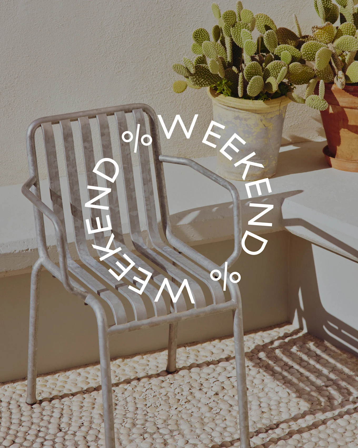 Sedia grigia a doghe metalliche accanto a un cactus in vaso, con testo circolare 'WEEKEND % WEEKEND %'.