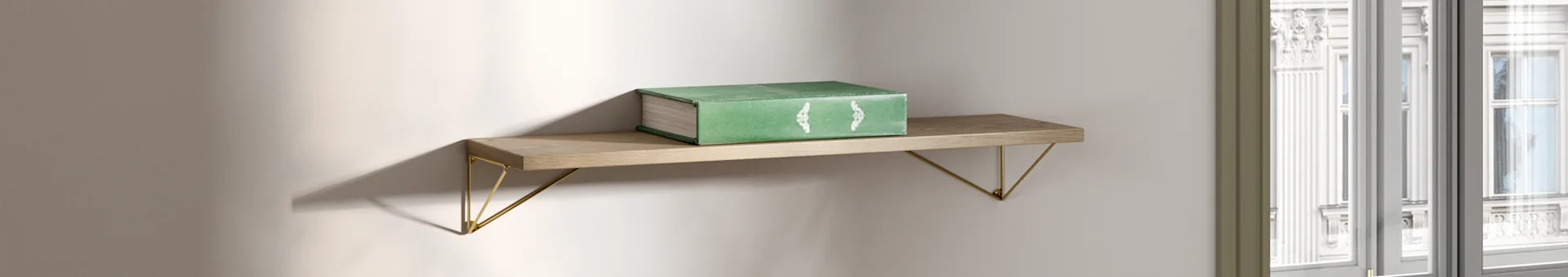 Un libro verde poggia su una mensola di legno con staffe dorate, illuminata dalla luce naturale vicino a una finestra.