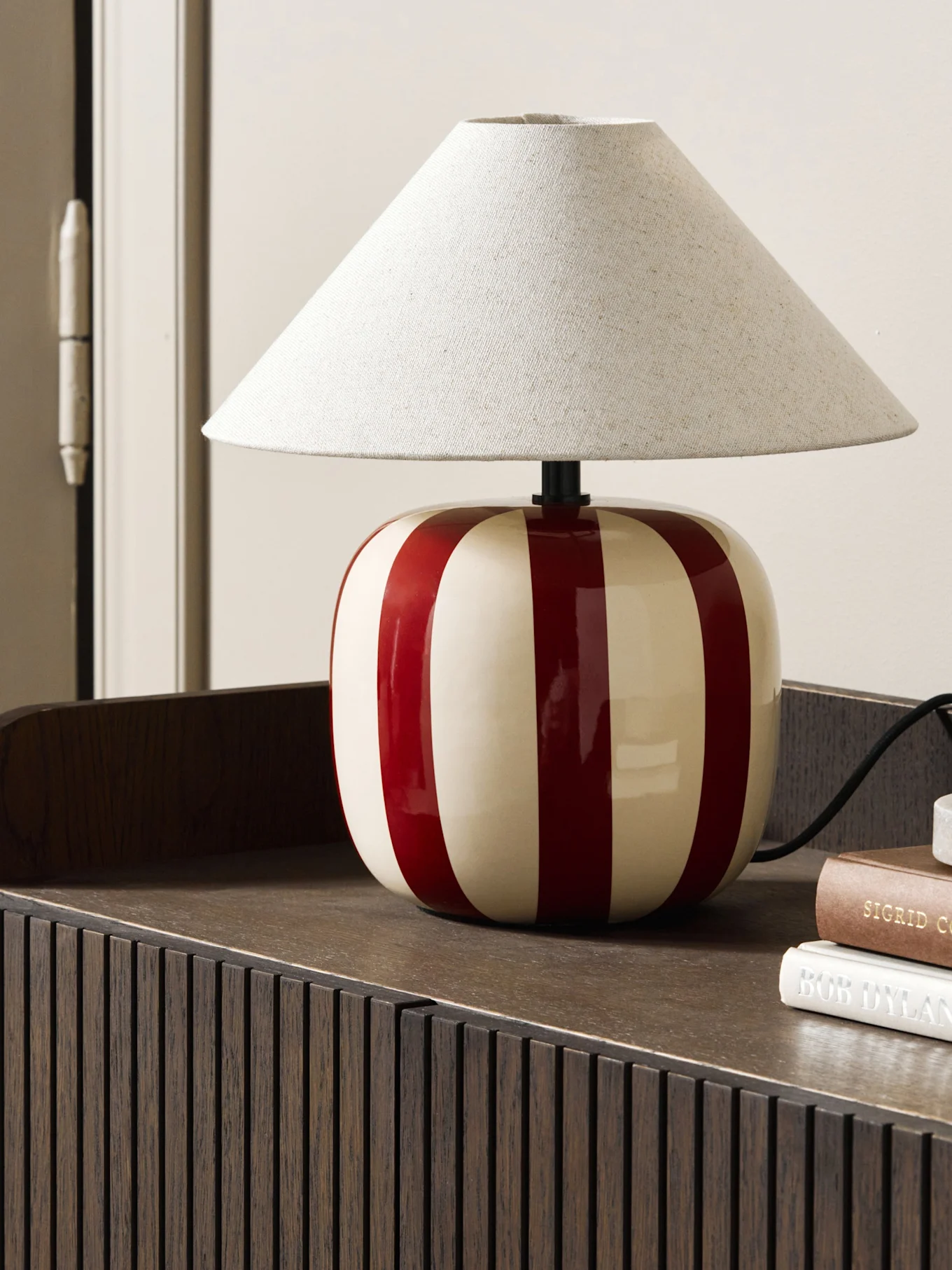 Lampada da tavolo blu chiaro a forma di fungo su un libro marrone-rossastro, su una mensola smerlata.