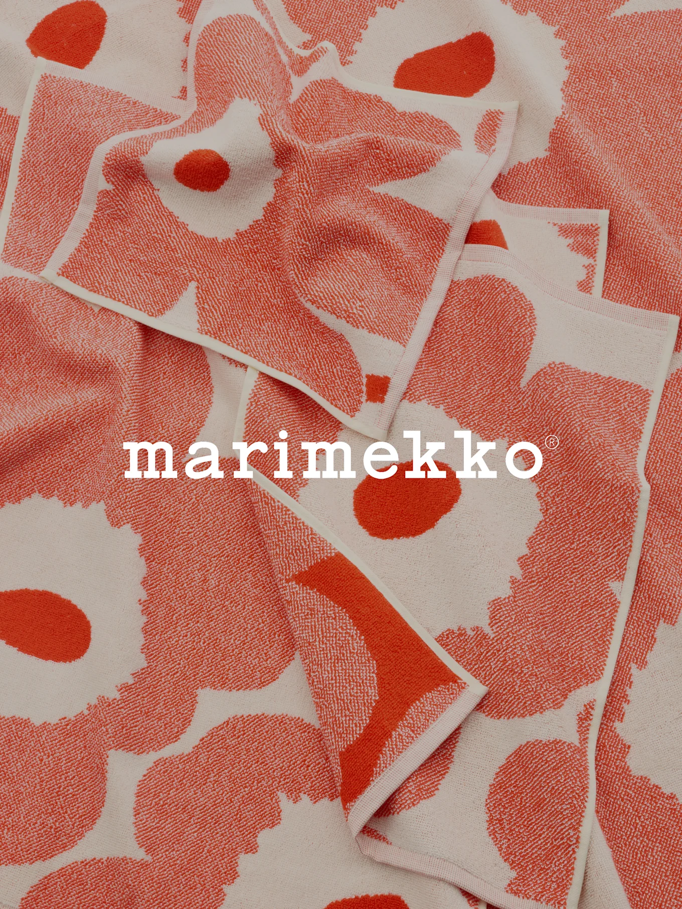 Asciugamani piegati con motivi corallo e bianco sporco e logo Marimekko.