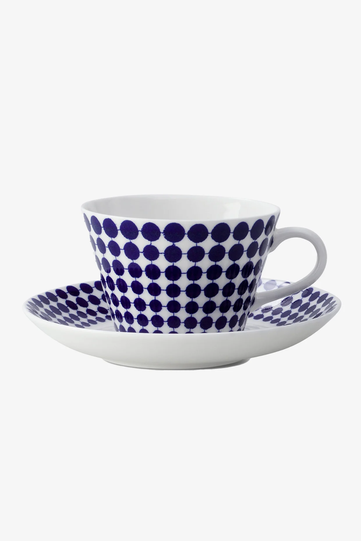 Tazza da tè e piattino bianchi con motivo a pois blu.