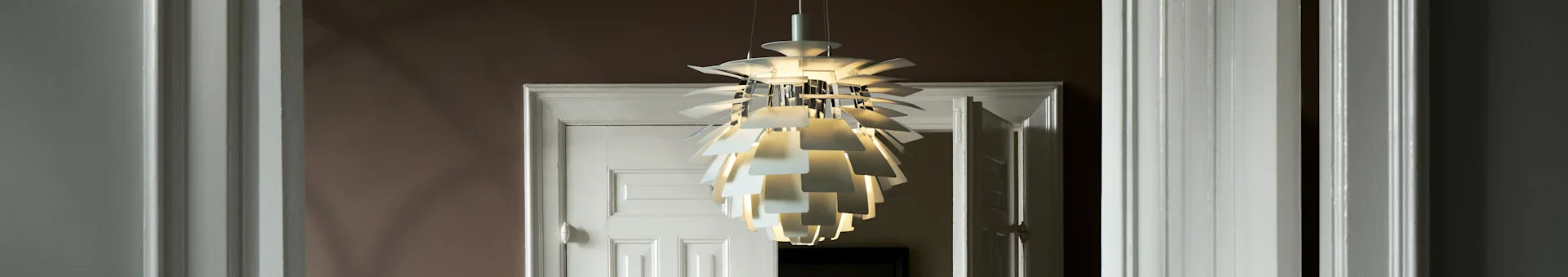 Una lampada a sospensione bianca e scultorea a più strati illumina una porta.