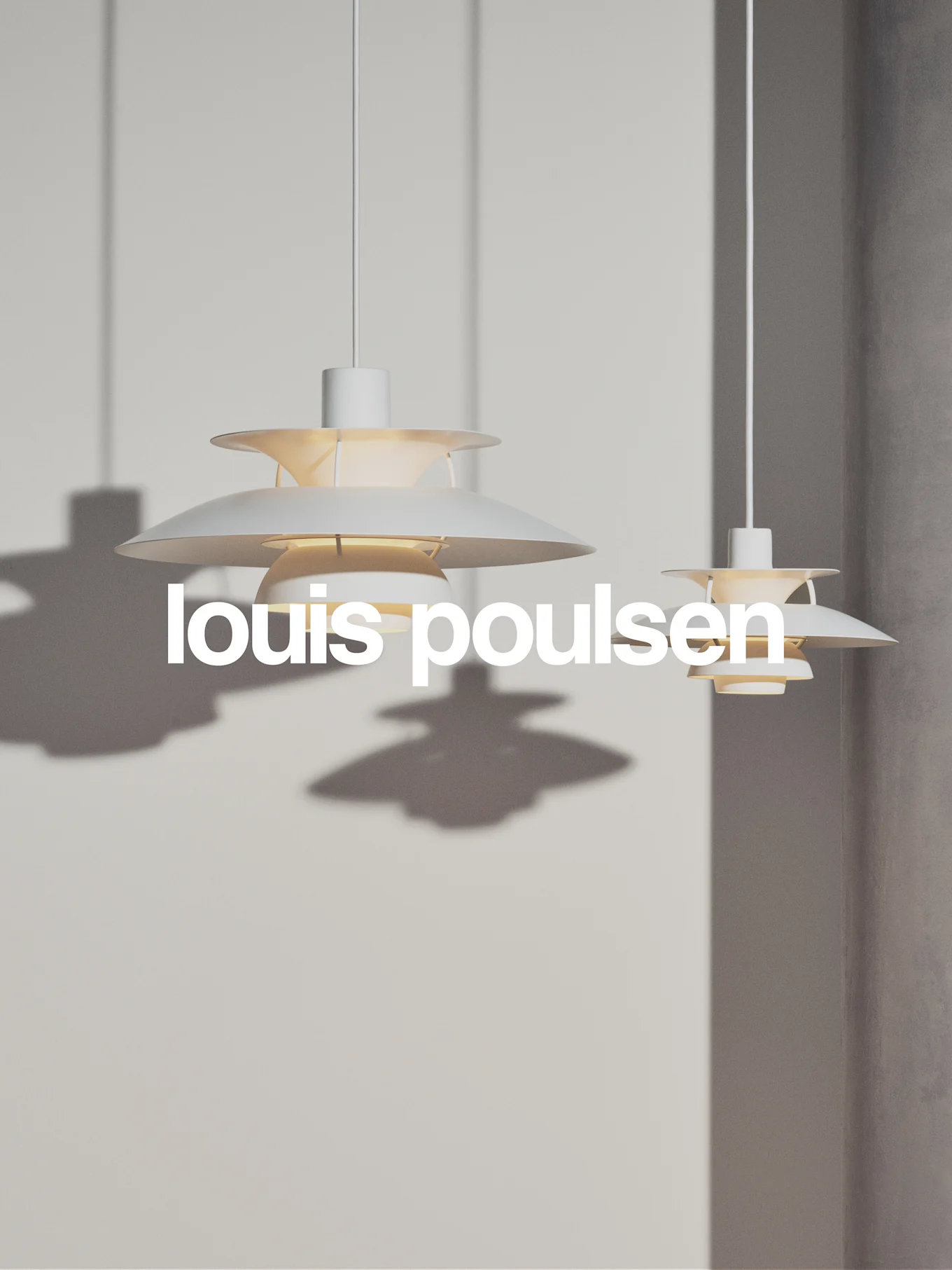 Due lampade a sospensione bianche a più livelli pendono contro una parete grigio chiaro, con il testo 'louis poulsen'.