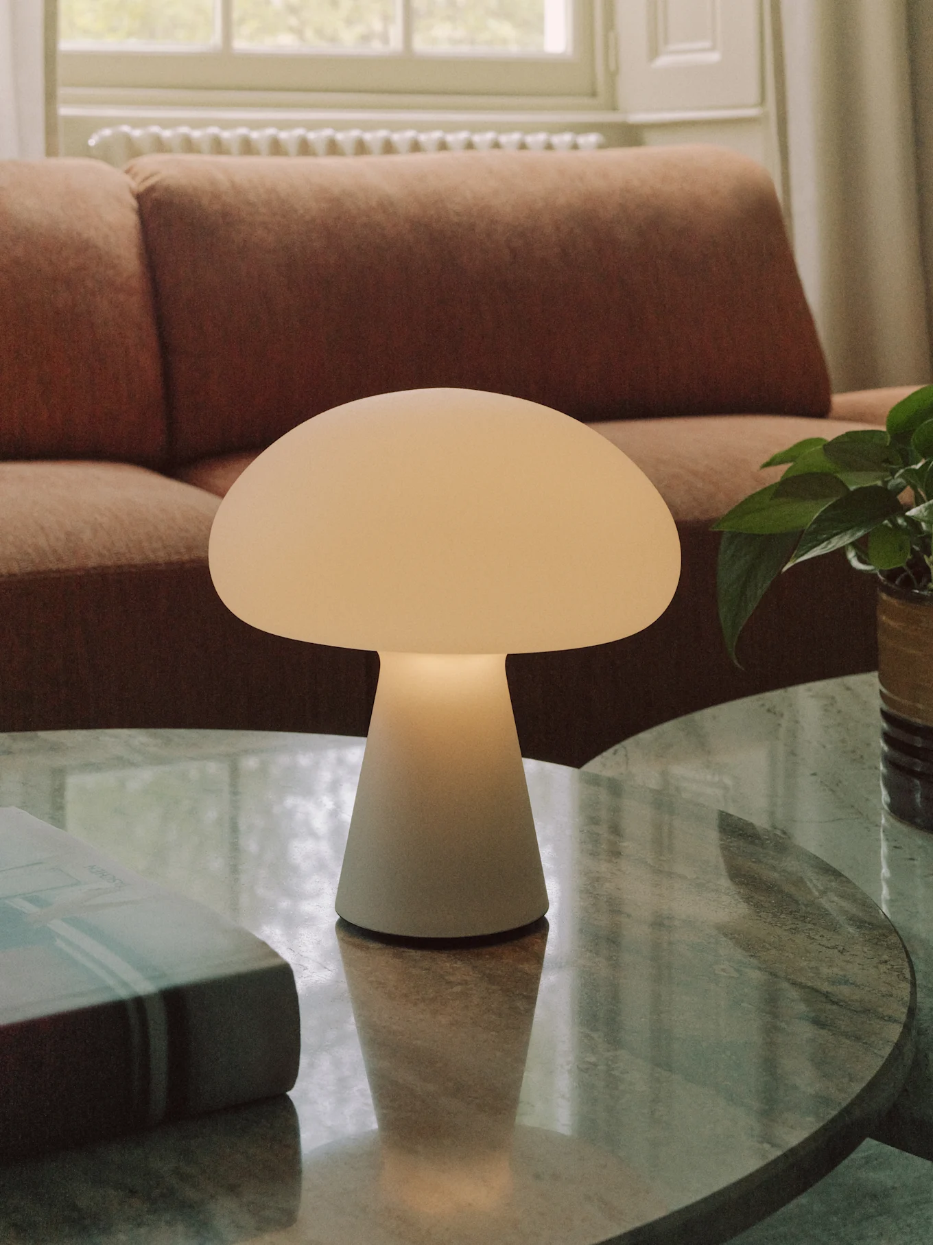 Una lampada da tavolo a forma di fungo bianco sporco su un tavolino da caffè rotondo in marmo in salotto.