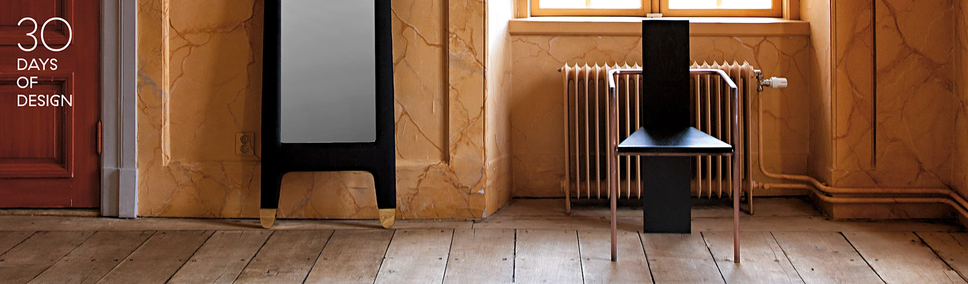 Sedia nera moderna con gambe in rame, alto specchio scuro con piedi dorati, in una stanza con pareti strutturate. Testo: 30 DAYS OF DESIGN.