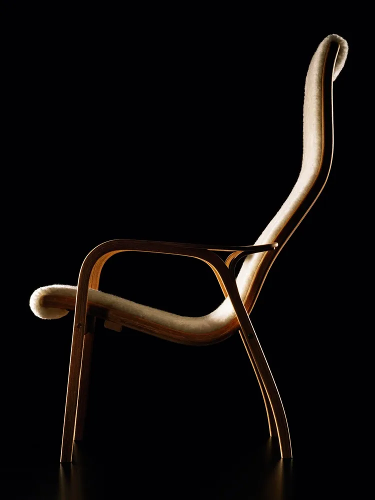 Una elegante poltrona lounge con struttura curva in legno chiaro e rivestimento in pelliccia crema, su sfondo nero.
