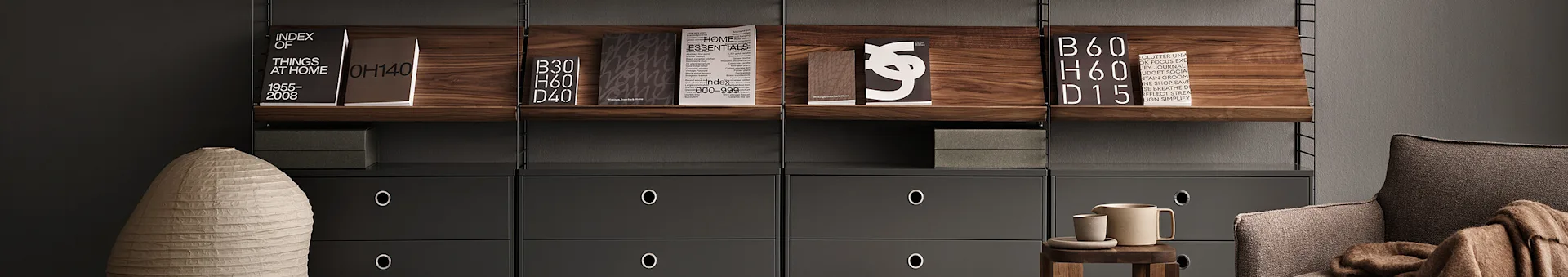 Scaffale moderno con ripiani in legno scuro, cassetti grigi, libri, un vaso chiaro, una poltrona marrone e accessori in ceramica.
