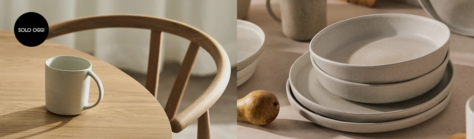 Tavolo in legno con tazza e sedia; a destra, pile di piatti e ciotole in ceramica beige con una pera. Solo Oggi.