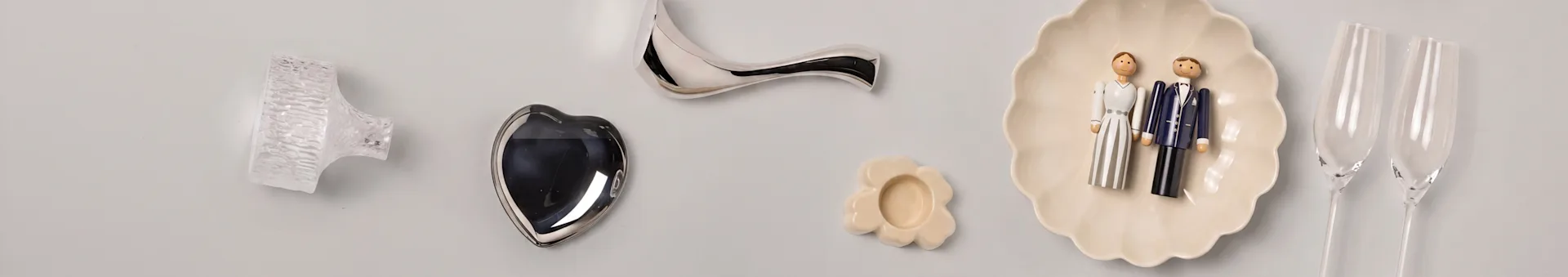 Oggetti decorativi: pomello di vetro, cuore d'argento, maniglia curva, piatto a fiore, statuette sposi, flûte champagne.